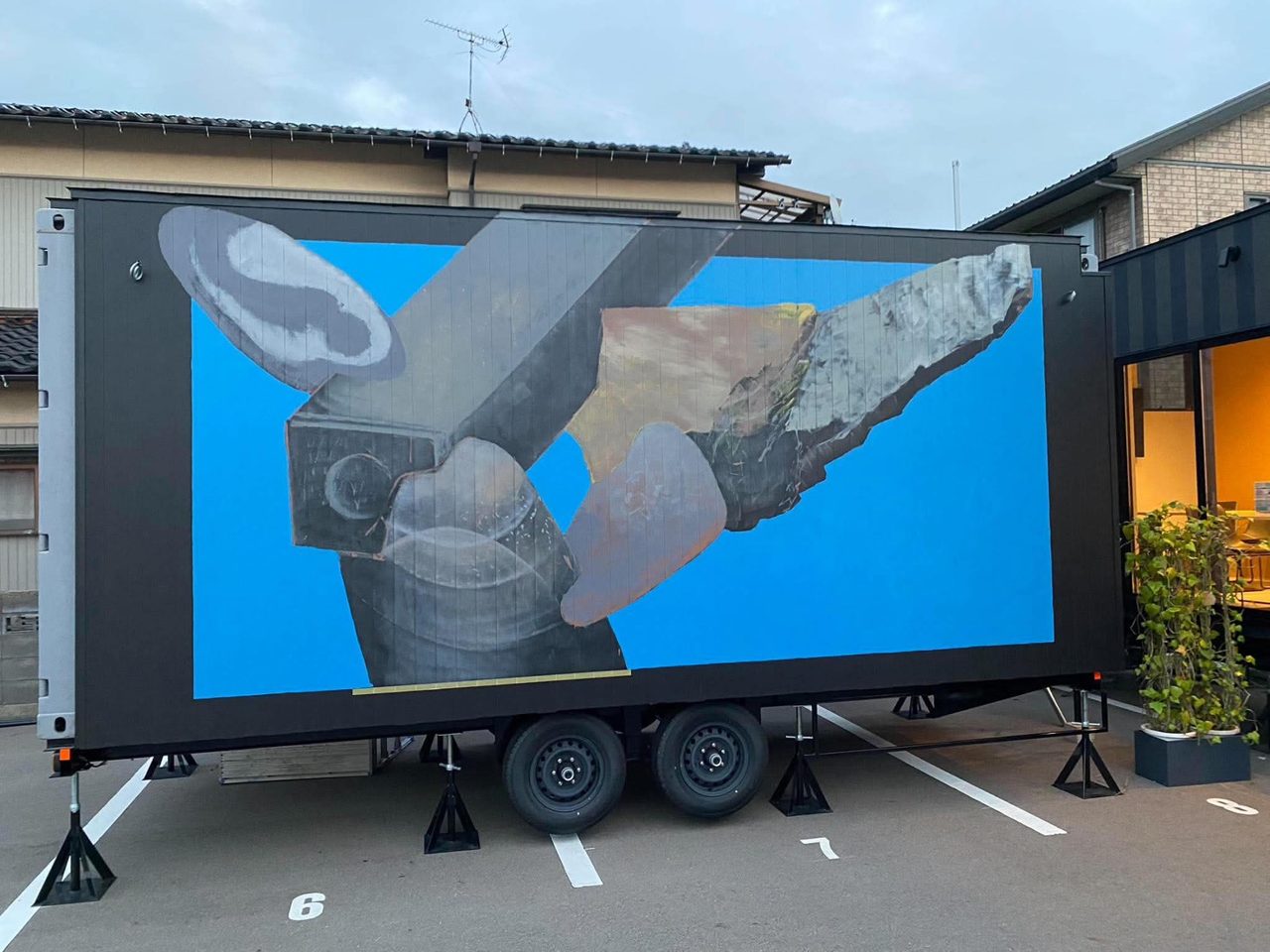 トレーラーハウスの側面に描かれた壁画。青い地に石のかたち